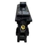 A black 20A circuit breaker with a gold screw terminal and white printed specifications, photographed on a light gray surface.
