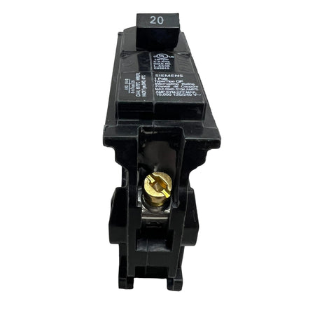A black 20A circuit breaker with a gold screw terminal and white printed specifications, photographed on a light gray surface.

